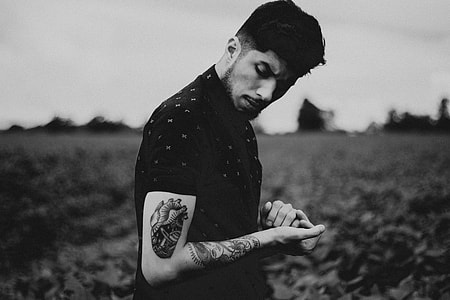 grayscale photography of man with tattoos thumbnail