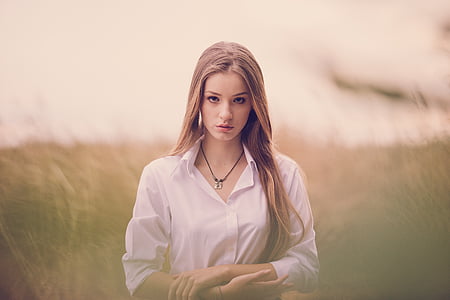 woman in white button-up collared long-sleeved shirt on grass field focus photography thumbnail