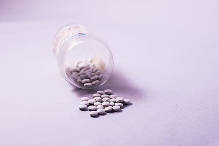 round white medication pills beside clear plastic container thumbnail