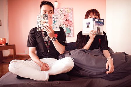 Couple Holding Books Sitting on Bed thumbnail