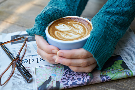 woman wearing blue sweater holding white coffee mug with espresso thumbnail