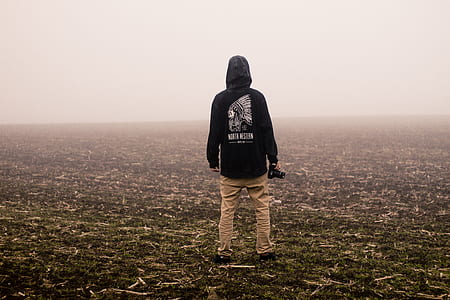 man wearing black hoodie while standing on plain thumbnail