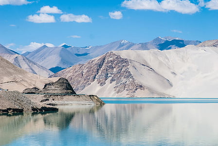 snow covered mountain range in front of body of water thumbnail