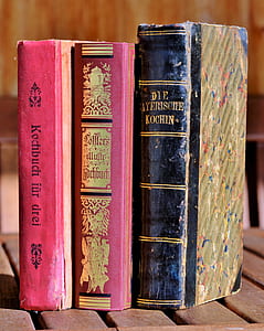 three assorted-title books on brown slatted table thumbnail