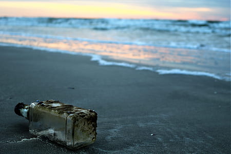 clear glass bottle on sands near shoreline thumbnail