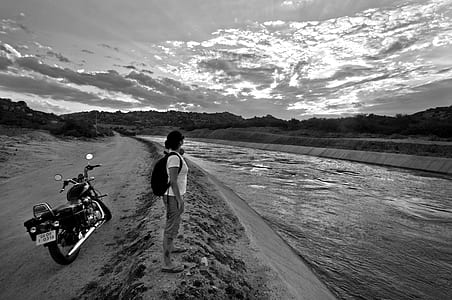 grayscale of person standing near touring motorcycle thumbnail