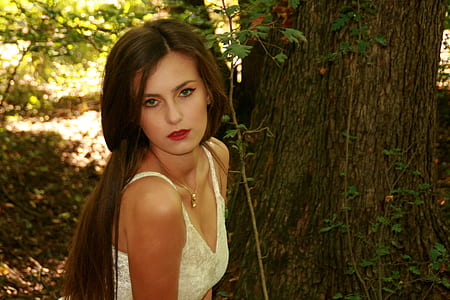woman wearing beige floral tank top near brown tree during daytime thumbnail