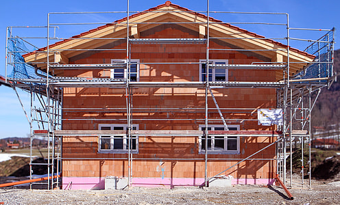 orange concrete house surrounded with grey scaffoldings thumbnail