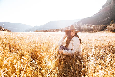 Woman Sitting on Grass Wearing Sun hat Field thumbnail