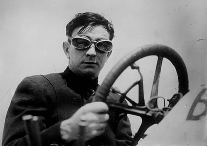 grayscale photography of man wearing goggles holding steering wheel thumbnail