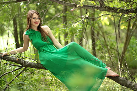 woman wearing green dress sitting on branch during daytime thumbnail