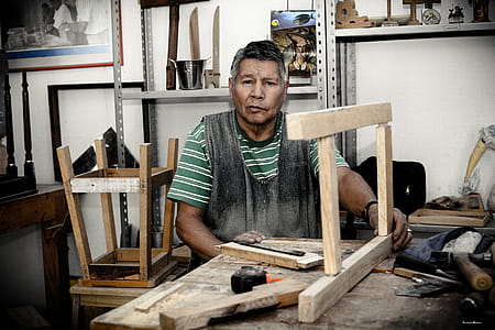 Man Wearing Green and White Stripe Shirt Holding Beige Wooden Frame on Table thumbnail