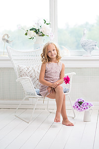 girl in beige dress holding a red flower sitting on a chair thumbnail