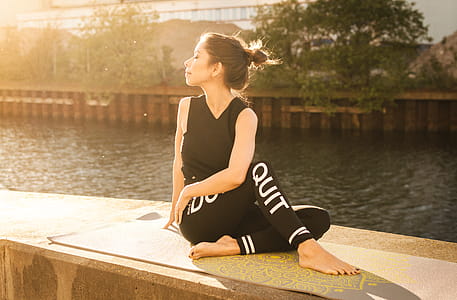 Woman Wearing Black Fitness Outfit Performs Yoga Near Body of Water thumbnail