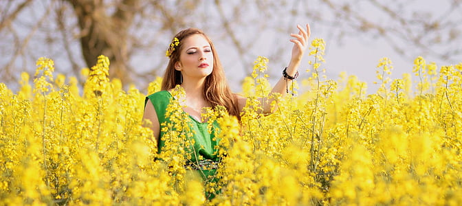 woman wearing green scoop-neck sleeveless top surrounded by yellow flowers thumbnail