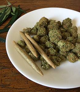 green kush in round white ceramic plate on top of brown wooden table thumbnail