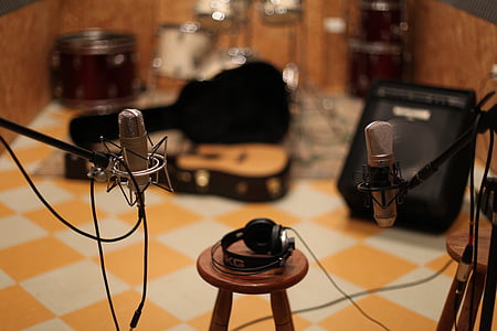 shallow focus photography of black headphones on brown wooden bar stool chair between microphones with stands thumbnail