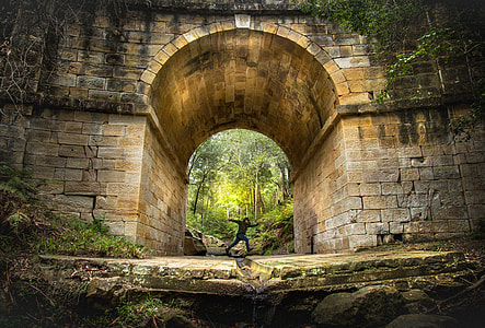 person in running gesture under brown concrete arch structure thumbnail