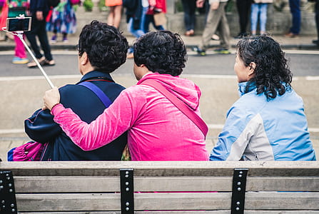 three people sitting on brown wooden bench thumbnail