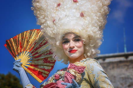 selective focus photography of woman holding red and beige folding fan thumbnail