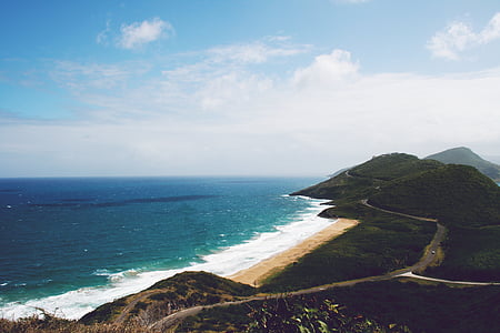 white and teal shoreline beside black dense forest under white and blue sky at daytime thumbnail