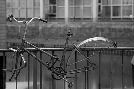 grayscale photography of hanged bicycle body frame on railing thumbnail