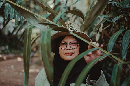 woman wearing brown hat holding green leafed plant thumbnail