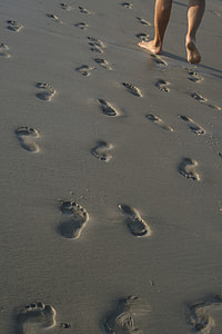 person walking on gray sand with footprints during daytime thumbnail