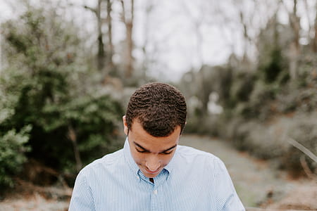 selective focus photography of man standing near trees and plant at daytime thumbnail