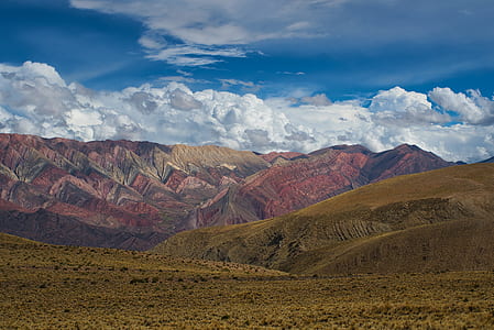 brown and green mountains under cloudy sky thumbnail