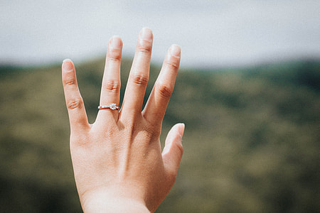 left human's hands wearing diamond solitaire ring thumbnail