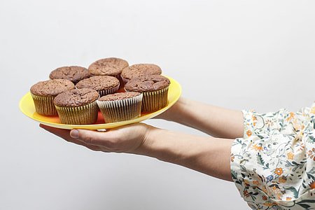 person holding yellow plate with cupcakes thumbnail