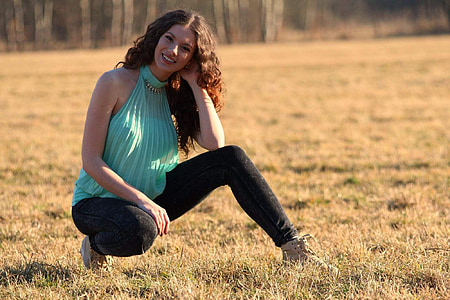 woman in teal top smiling while sitting on grass field thumbnail