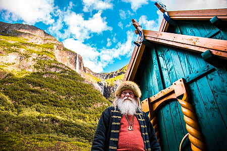 man standing beside a teal and brown wooden house thumbnail
