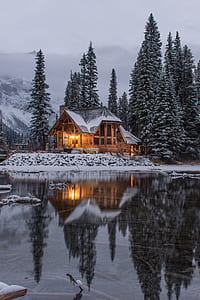 rest house with lights turned on near lake during winter thumbnail