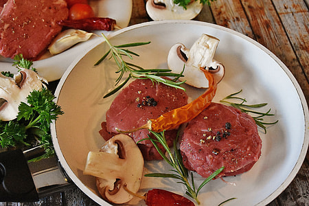 marinated raw meat between sliced two mushrooms on top ceramic plate thumbnail