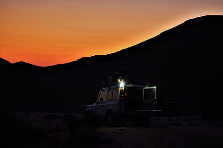 blue vehicle beside silhouette of mountain at sun down thumbnail