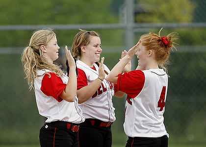 three blonde women wearing white-and-red jersey tops outdoors thumbnail