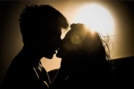 silhouette of man and woman kissing under sun thumbnail