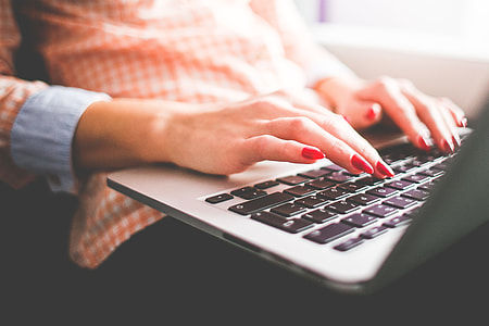 women's wearing orange and white stripped button-up shirt touching MacBook Air thumbnail