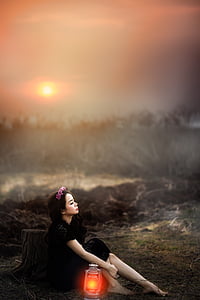woman sitting on the ground beside the kerosene lamp thumbnail