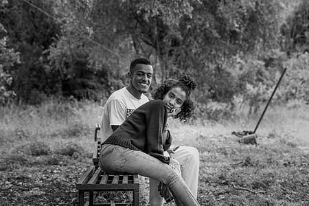 grayscale photography of couple sitting on bench smiling thumbnail