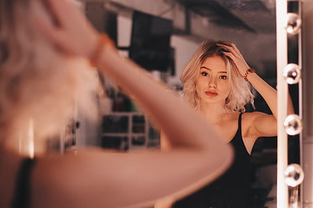 woman facing mirror fixing her hair inside room thumbnail