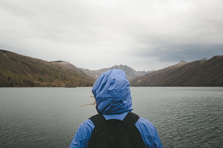 person wearing blue hoodie facing on body of water during daytime thumbnail