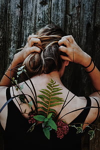 woman holding her hair with both hands with plants on her back thumbnail