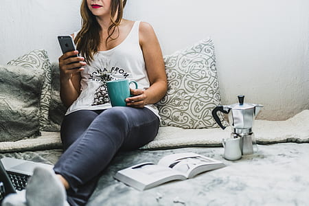 woman sitting on bed holding space gray iPhone 6 and teal mug thumbnail