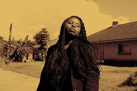 woman standing near brown house during daytime thumbnail