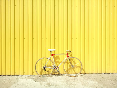 white and red road bike near yellow fence thumbnail