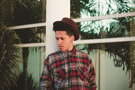 man in brown fedora hat leaning on white pole thumbnail