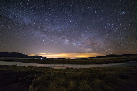 lake surrounded by green grass field under starry night thumbnail